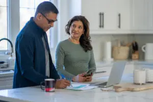 Couple working at kitchen table with laptop.